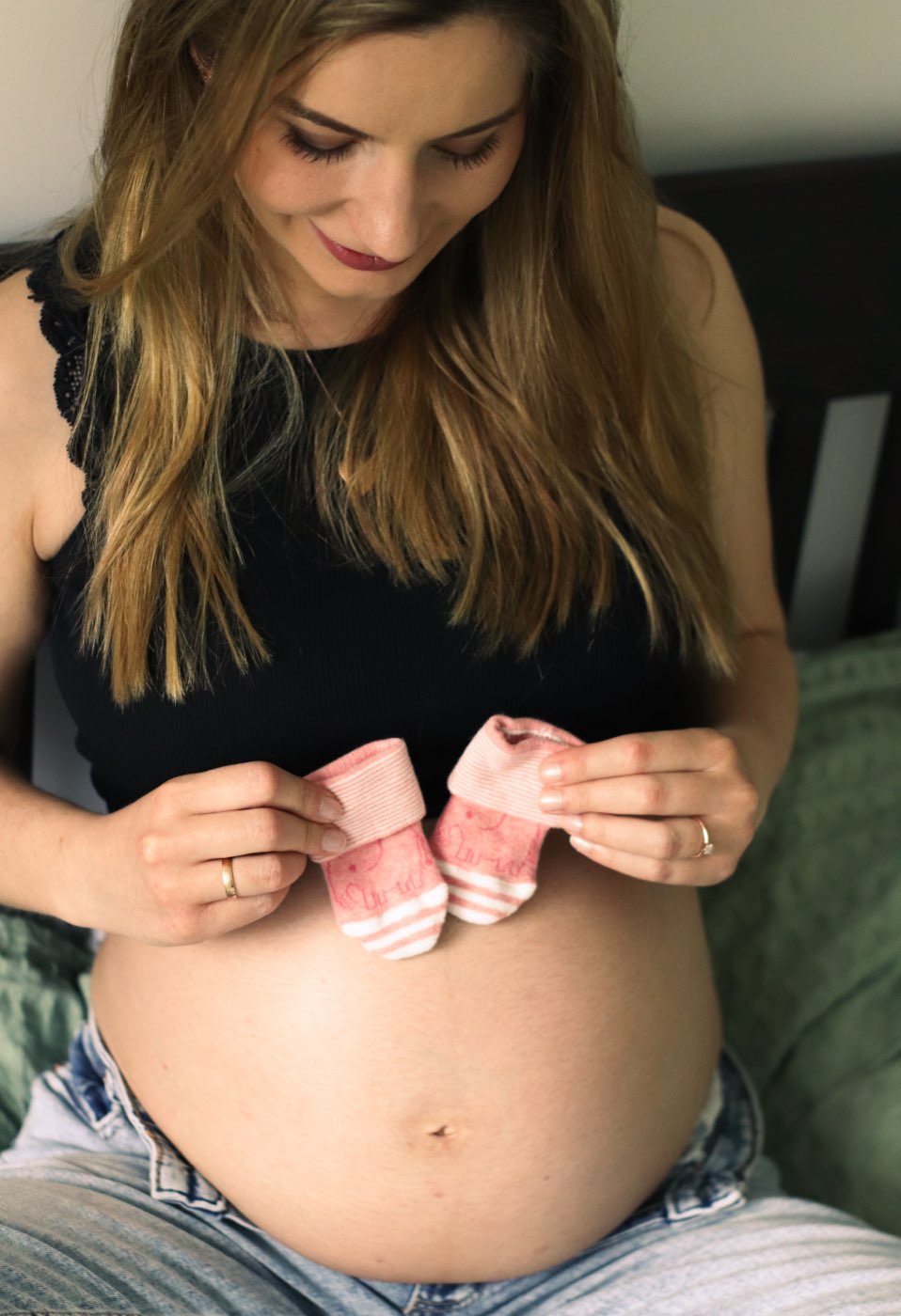 Eine Schwangere hält ein Paar kleine Babysocken über ihren Bauch