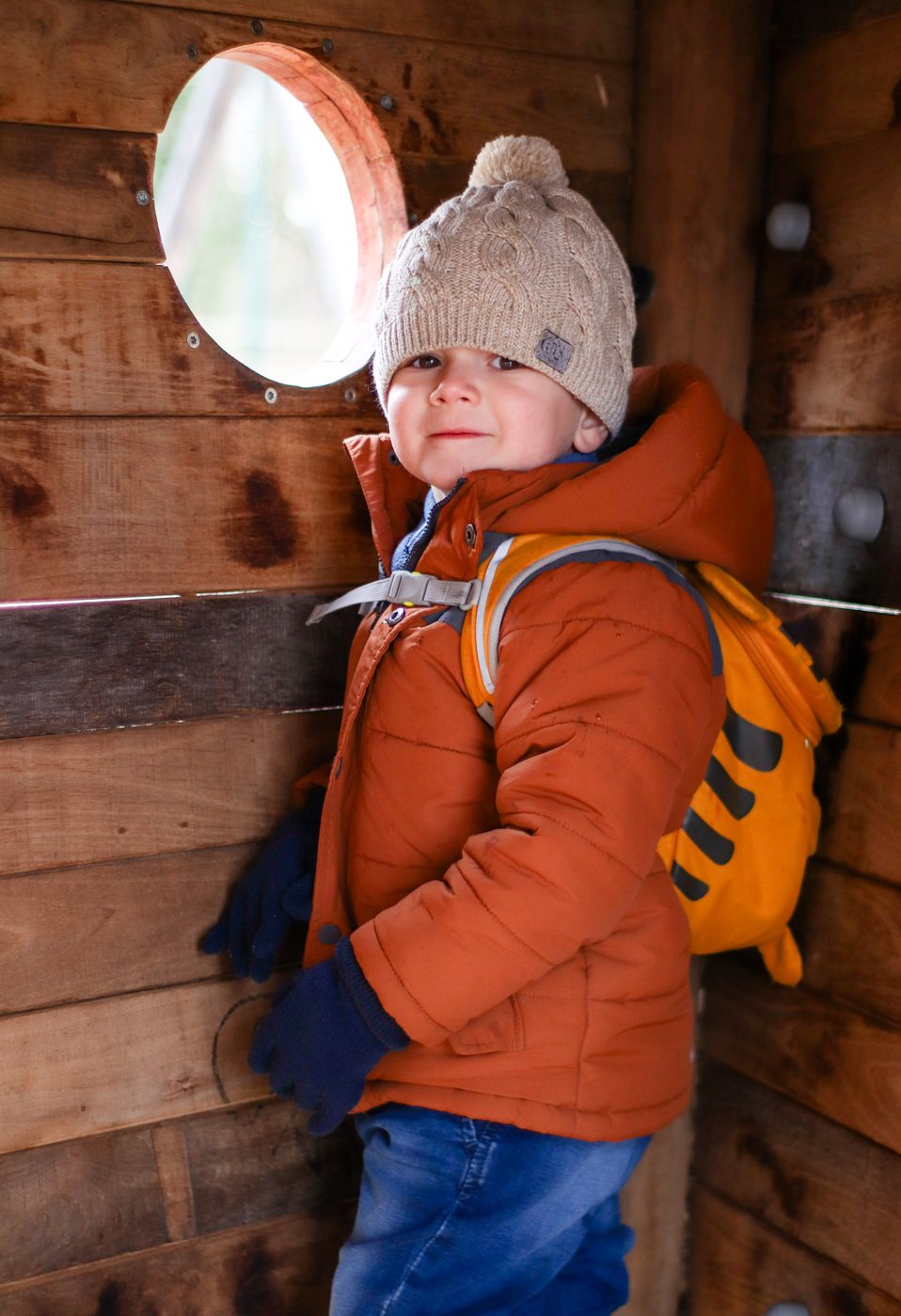 Der Bub lehnt in einem Spielh&auml;uschen aus Holz