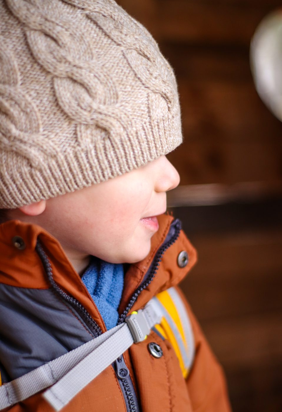 Der Bub im Profil, mit Haube und Rucksack