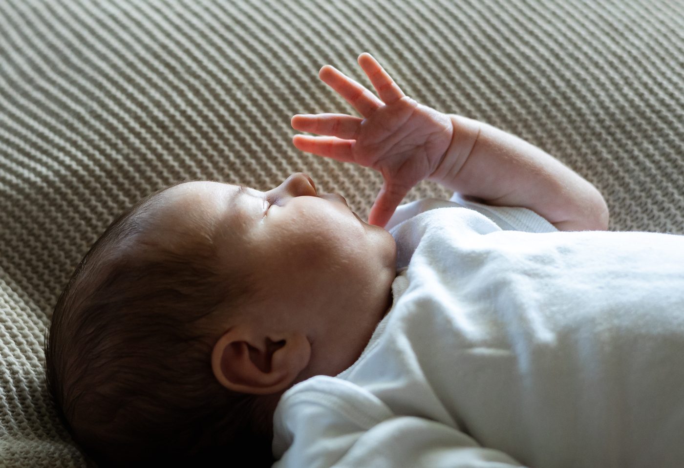 Ein Baby streckt im Schlaf seine kleine Hand in die Luft