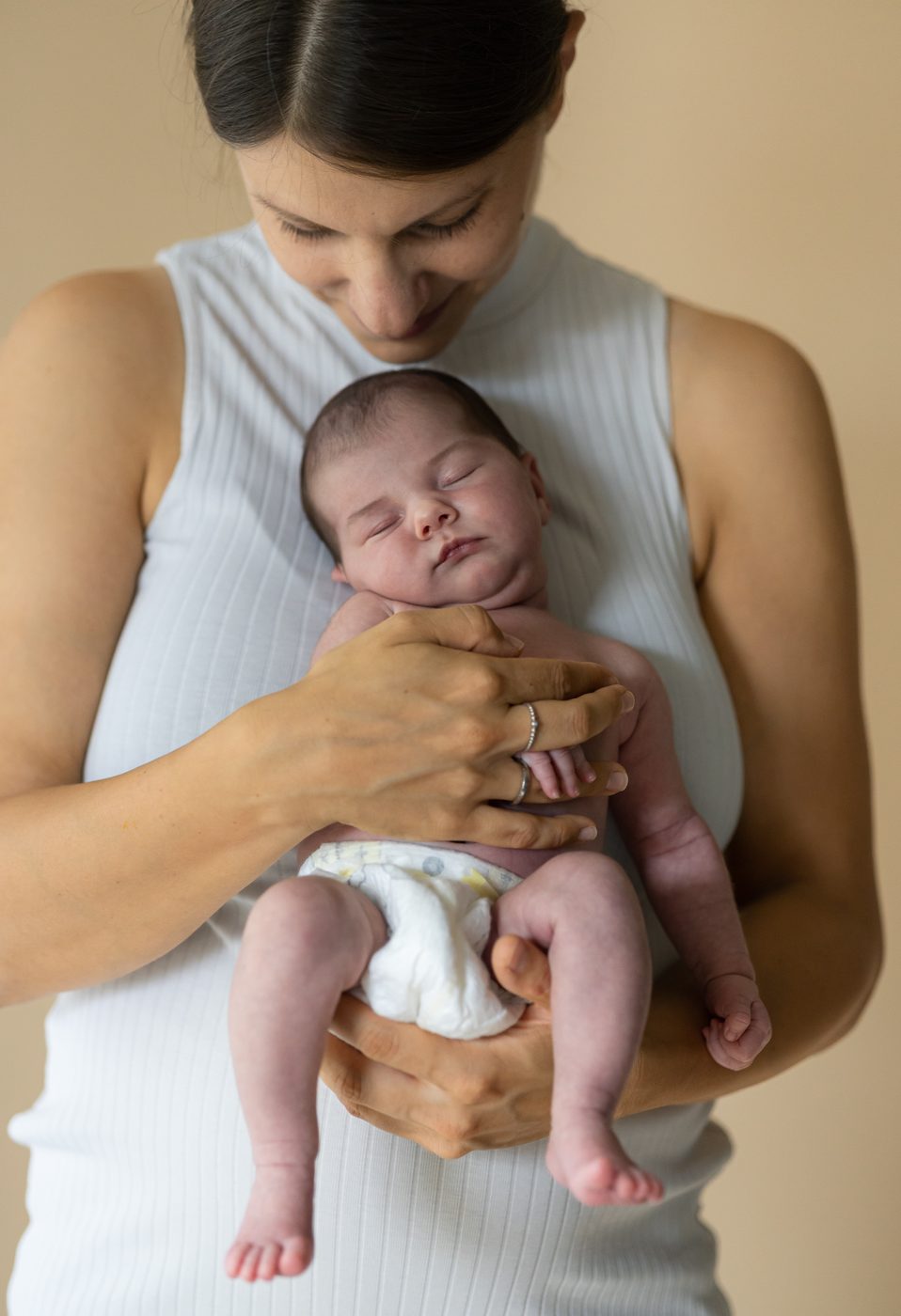 Eine Mama h&auml;lt ihr Neugeborenes nah an ihrer Brust und sieht es an
