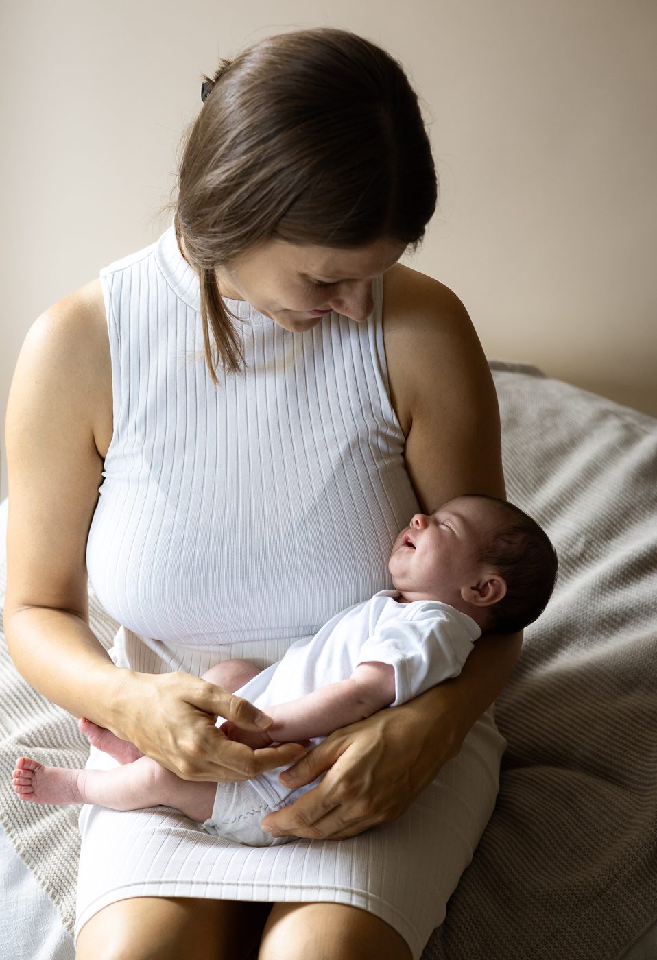 Eine Mama sitzt mit ihrem Baby auf dem Scho&szlig; und betrachtet es liebevoll