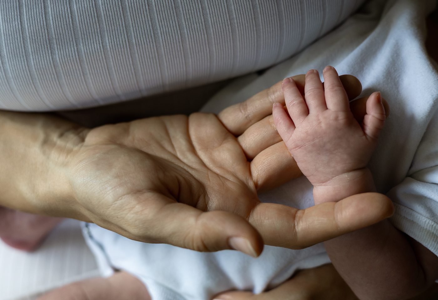 Eine Babyhand ruht in der offenen Hand der Mama
