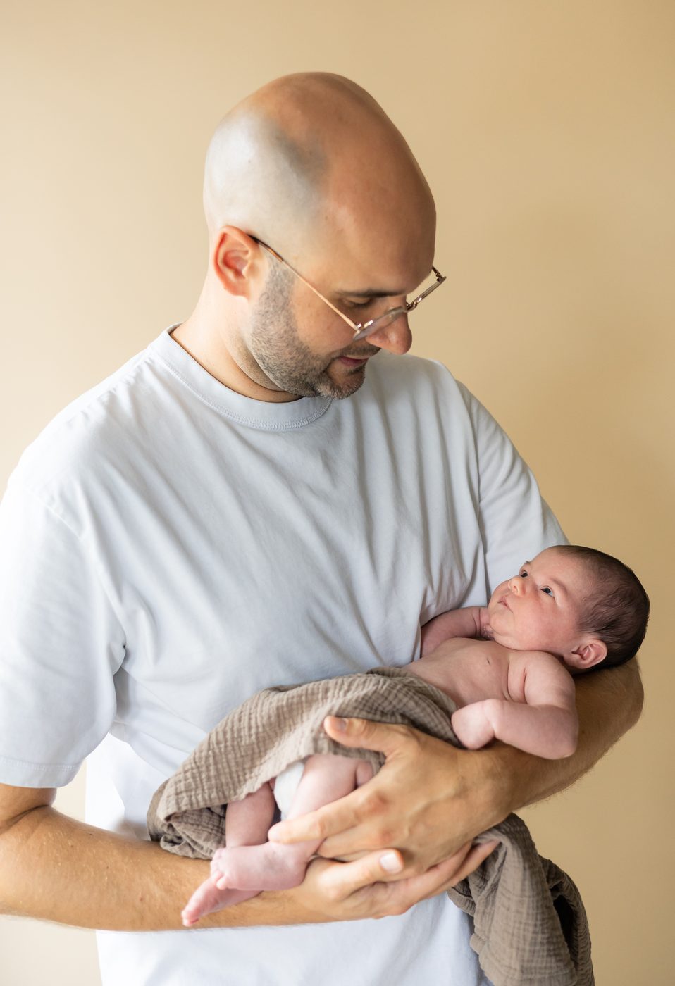 Ein Papa h&auml;lt sein Neugeborenes im Arm und l&auml;chelt es an