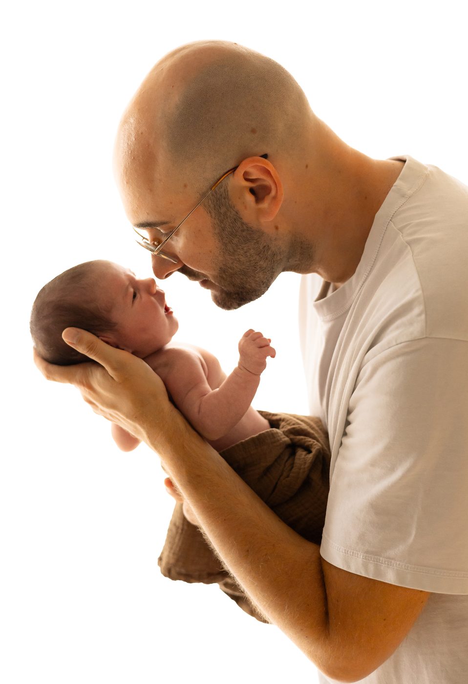 Ein Papa h&auml;lt sein Baby hoch und ber&uuml;hrt es Nase an Nase